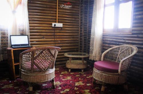 大吉嶺的住宿－Spring Brooks Homestay，一间设有两把椅子和一张桌子上的笔记本电脑的房间