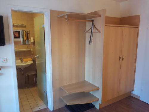 uma casa de banho com um armário com prateleiras e um lavatório em La Locanda Ristorante Pizzeria Garni em Ohlstadt