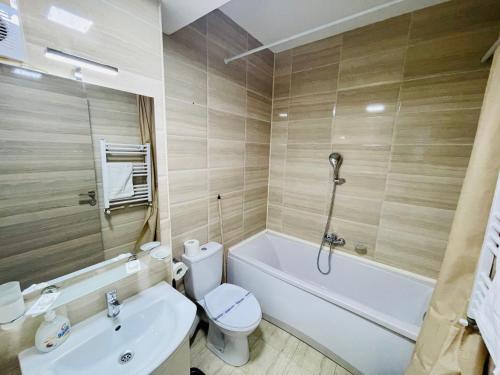 a bathroom with a toilet and a tub and a sink at Summerland Studios Nuba in Mamaia