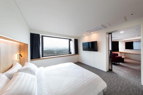 a hotel room with a large white bed and a window at Seoul Olympic Parktel in Seoul