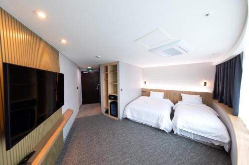 a hotel room with two beds and a flat screen tv at Seoul Olympic Parktel in Seoul