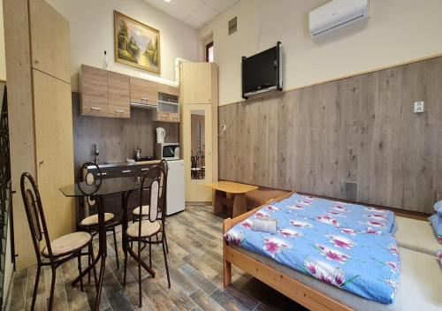 a room with a bed and a table and a kitchen at Oázis Apartman in Harkány