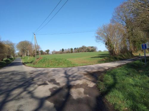 an empty road with a green field in the distance at Craftycotta in Glomel