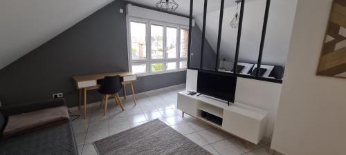 uma sala de estar com uma televisão, uma mesa e uma janela em Appart'Hôtel - Chateaubriant em Châteaubriant