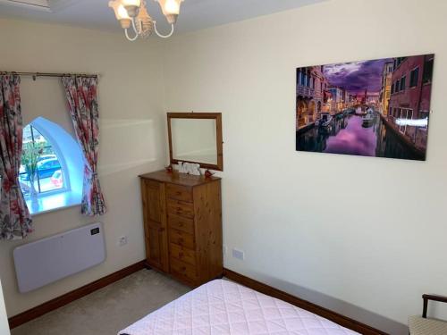 a bedroom with a dresser and a mirror on the wall at Cut Limestone Apartment Riverside Lodge in Carlow