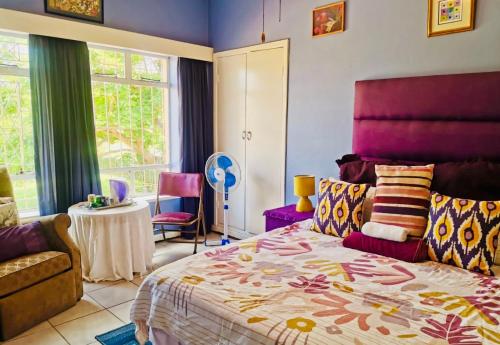 a bedroom with a bed and a couch and a table at Su Casa Scottsville in Pietermaritzburg