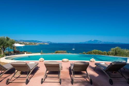 a group of chairs sitting next to a swimming pool at Villa Carvella - A Sublimely Relaxing Escape! in Tsilivi