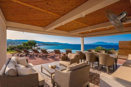 a patio with chairs and tables and a view of the water at Villa Carvella - A Sublimely Relaxing Escape! in Tsilivi