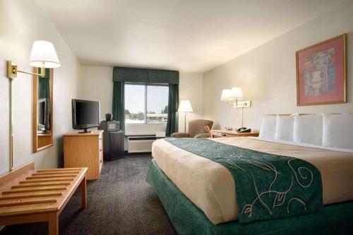 a hotel room with a large bed and a television at Travelodge by Wyndham Cheyenne in Cheyenne