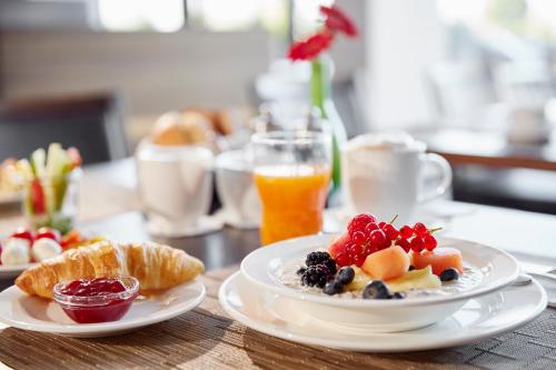 a table with two plates of breakfast foods and orange juice at Lindner Hotel Nurburgring Motorsport, part of JdV by Hyatt in Nürburg