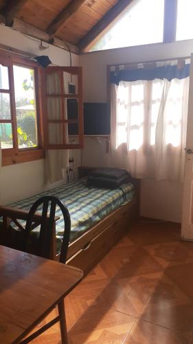 een kleine kamer met een bed, een tafel en ramen bij Cabañas El Abuelo Alfredo in Ciudad Lujan de Cuyo