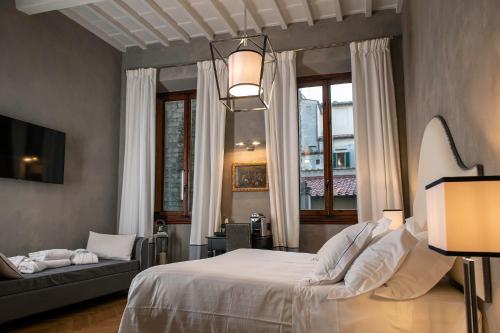 a bedroom with a bed and a couch and windows at Relais Uffizi in Florence