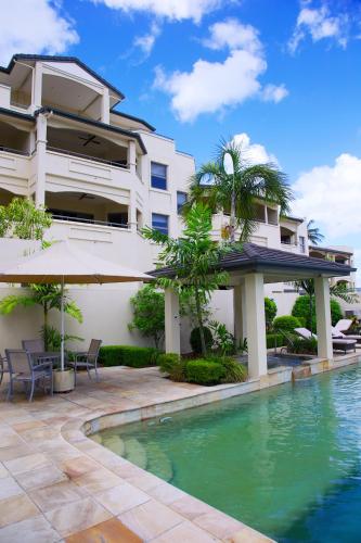 a villa with a swimming pool in front of a building at Portside Whitsunday Luxury Holiday Apartments in Airlie Beach