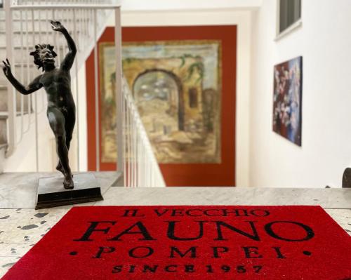 a statue sitting on a table next to a red rug at Il vecchio Fauno in Pompei