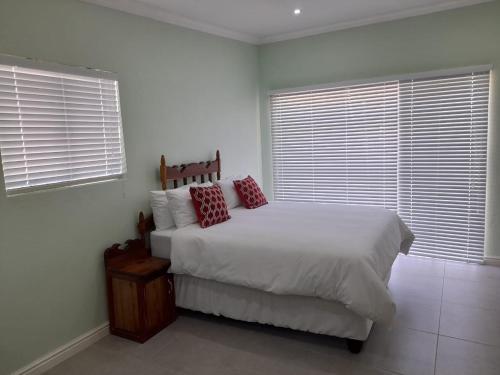 a bedroom with a white bed and two windows at 7 On Strauss in Beaufort West
