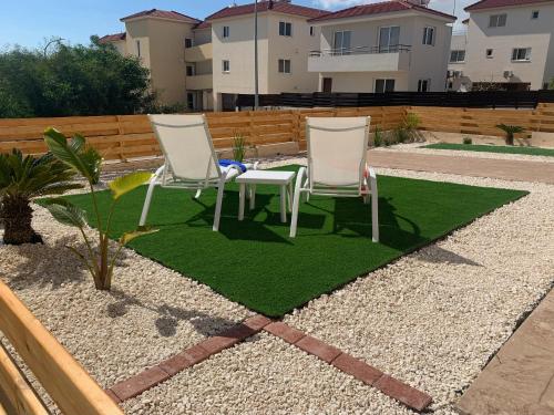 twee stoelen en een tafel op een grasveld bij Nissi3 B1 Lovely 1Bdr Ground Floor Apartment near Nissi Beach. in Ayia Napa