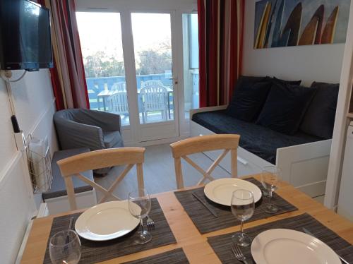 Un comedor con una mesa y sillas y un sofá. en Vue Golf dans Résidence Nature "SYMPALAPPART", en Moliets-et-Maa