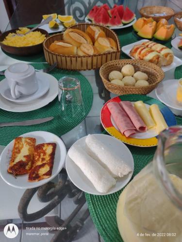 a table topped with plates of food and bowls of bread at Blue Hostel in Natal