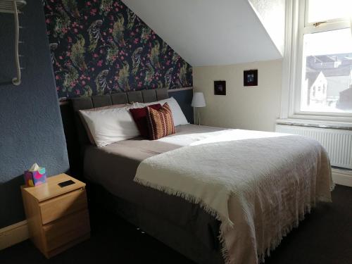 1 dormitorio con 1 cama grande y papel pintado con motivos florales en The Manhattan, en Blackpool