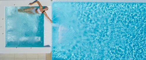 a person is pouring water into a swimming pool at Soleila Mykonos Villa in Kalafatis
