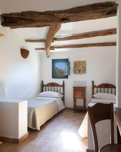 two beds in a room with white walls and wooden ceilings at Stazzo Lu Ciaccaru in Arzachena