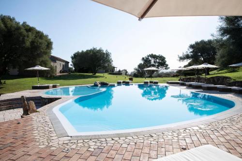 a large swimming pool in a yard with umbrellas at Stazzo Lu Ciaccaru in Arzachena