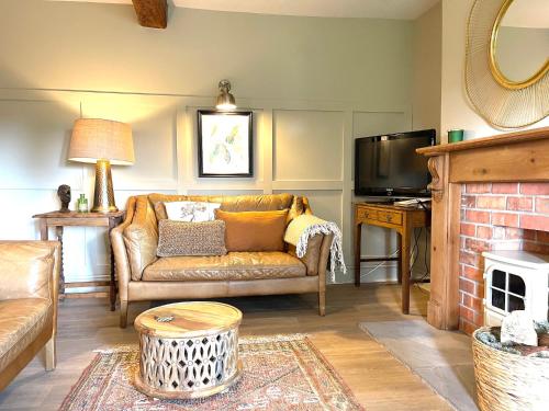 uma sala de estar com um sofá e uma televisão em The Cottage, Yew Tree Farm Holidays, Tattenhall, Chester em Tattenhall