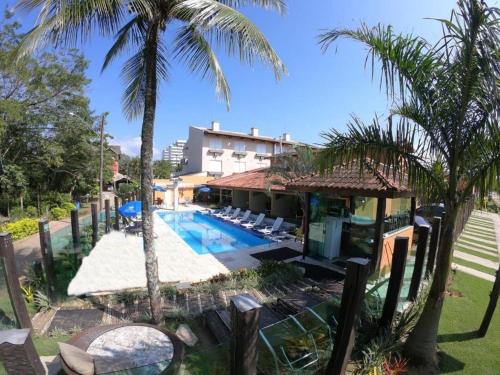 a resort with a swimming pool and palm trees at Pousada Acqua Infinity PISCINA CLIMATIZADA PÉ NA AREIA in Bertioga