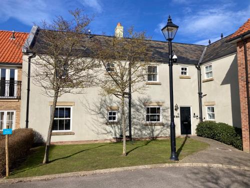 una casa blanca con una luz de la calle delante de ella en Filey Hideaway Apartment The Bay Holiday Village Filey Homesweetholidayhomes, en Filey