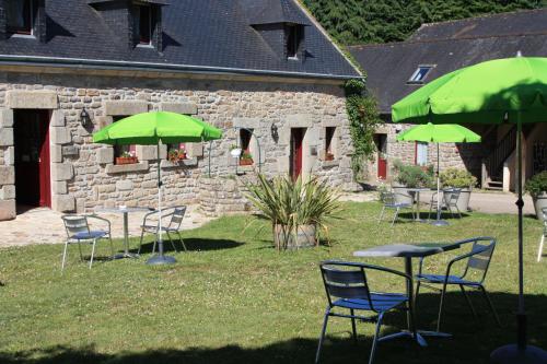 un groupe de tables et de chaises avec des parasols verts dans l'établissement Domaine de Lesvaniel, à Landudec