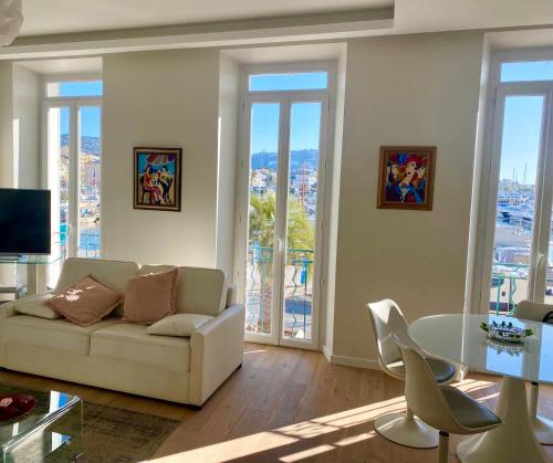 a living room with a couch and a table with chairs at Cannes Vieux Port Seafront & Seaview, fast wifi in Cannes