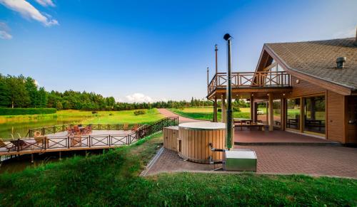 a building with a deck next to a river at Harmony Park Countryside Villas & SPA in Prienai