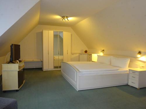 a bedroom with a white bed and a television at Ferienwohnung Pension Sigwarth in Belgern