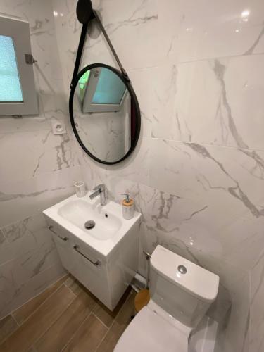 La salle de bains blanche est pourvue de toilettes et d'un miroir. dans l'établissement Studio Le Pénéqué des Anges, à La Ciotat