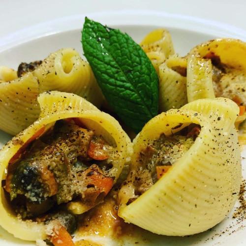 a plate of pasta with pesto and a green leaf at Nymfasia Resort in Vytina