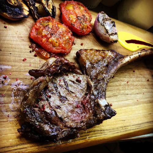 a cutting board with steak and vegetables on it at Nymfasia Resort in Vytina