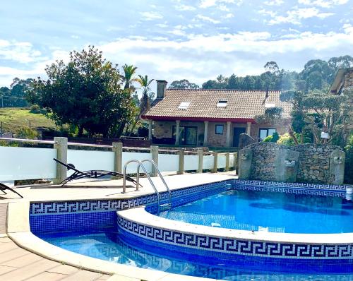 a swimming pool in front of a house at VILLA RAICES. Agradable casa con piscina in Baiona