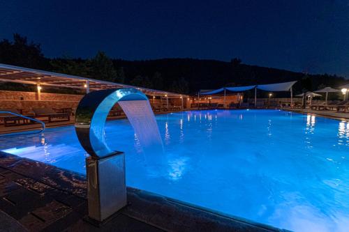 a large blue swimming pool at night at Nymfasia Resort in Vitina