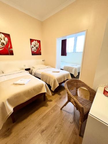 a room with three beds and a chair in it at Melbourne House Hotel in London