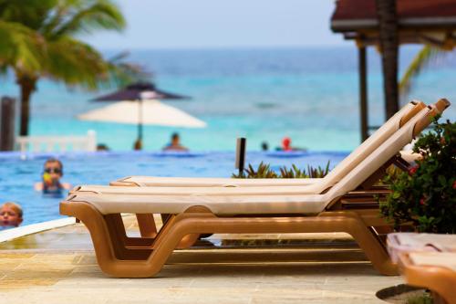 a lounge chair at a beach with people in the water at Infinity Bay Spa & Beach Resort in West Bay