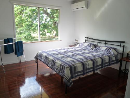 1 dormitorio con 1 cama con manta a cuadros y ventana en Elliot River Retreat - Pet Friendly, en Guthalungra