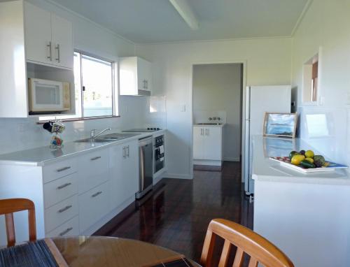 a kitchen with white cabinets and a table with a bowl of fruit at Elliot River Retreat - Pet Friendly in Guthalungra