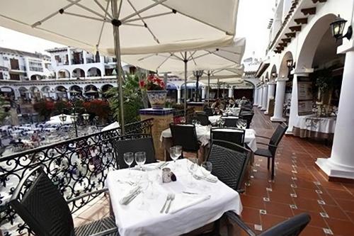 um restaurante com mesas brancas, cadeiras e guarda-sóis em Apartment on the Plaza em Alicante