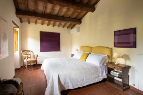 a bedroom with a white bed and a chair at La Fattoria del Rio di Sopra - Agriturismo Baldeschi in Tuoro sul Trasimeno