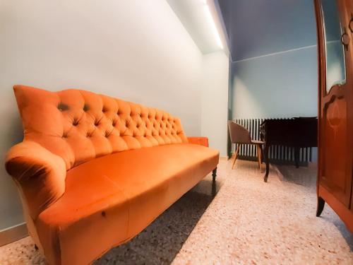 an orange couch in a room with a chair at Palazzo Romanelli B&B in Trani