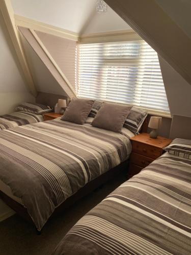 a bedroom with three beds and a window at Westdene in Skegness
