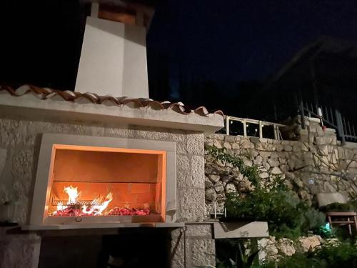 a stone fireplace with a fire in it at night at Mala Cele in Podgora