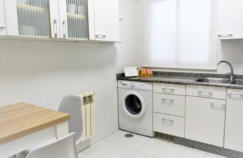 a white kitchen with a washing machine in it at Santiago Apartment in Santiago de Compostela