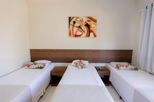 a room with two beds and a painting on the wall at Pousada Pontal in Curvelo