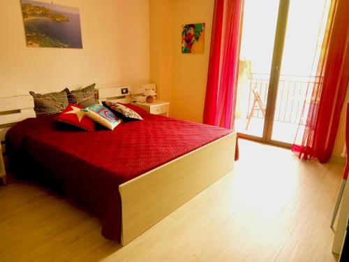 a bedroom with a bed with red sheets and a window at Villa i Minnulareddi in Giardini Naxos